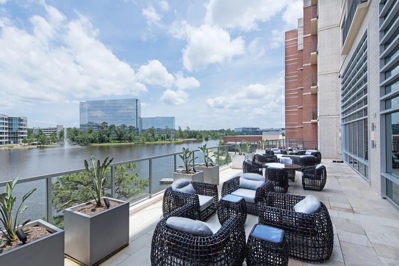 Modern corporate terrace with wicker lounge seating overlooking serene fountain lake