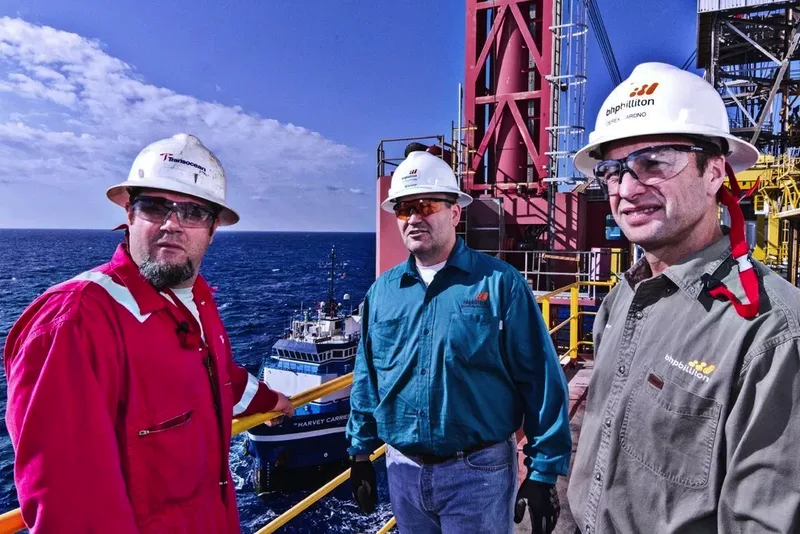 Corporate environmental portrait of three offshore oil platform workers in branded hard hats