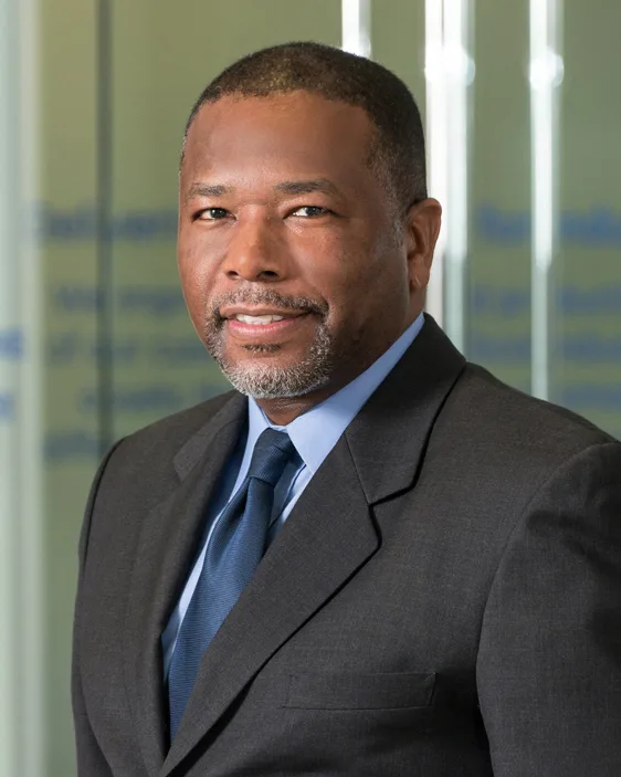 Executive portrait man in charcoal suit blue tie blurred glass background