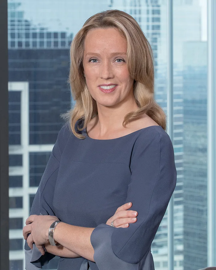 On-site headshot professional woman grey blouse arms crossed glass office windows