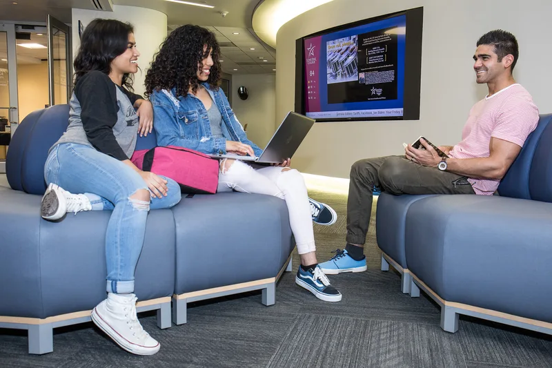 college students socializing in modern campus lounge with open laptop